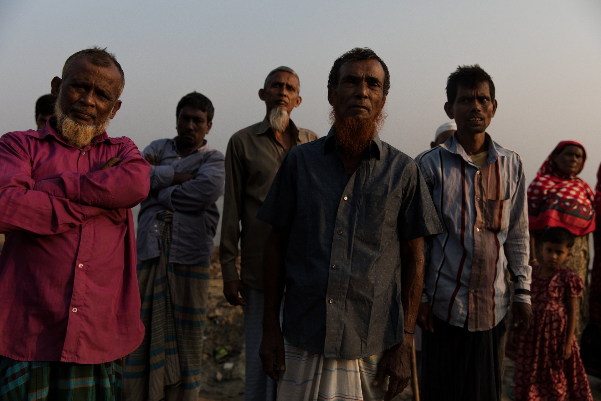 A man, standing in a group, who has lost his home twice due to land erosion 