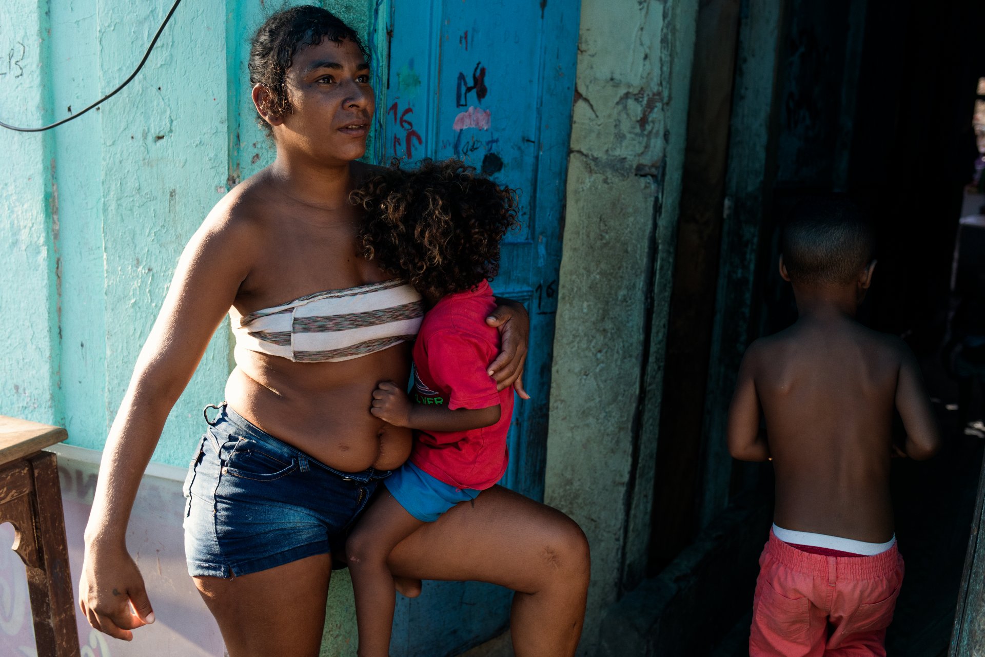 Woman holding her young son on the porch where she was shot while pregnant with him