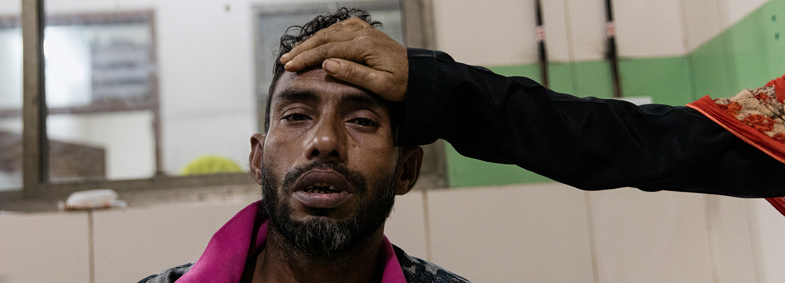 Man with suspected dengue fever sitting on a bed at Dhaka Medical Hospital