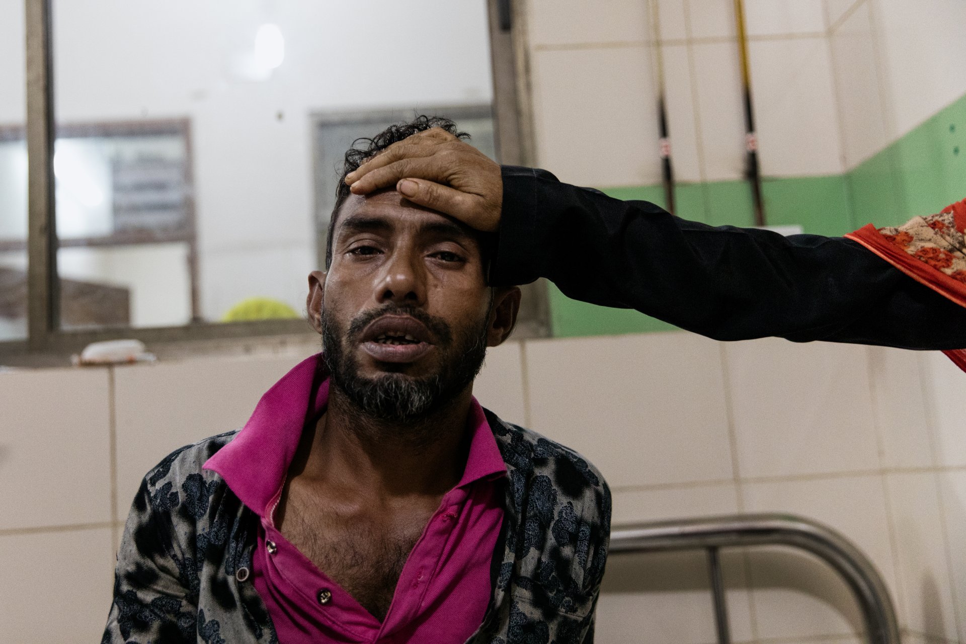 Man with suspected dengue fever sitting on a bed at Dhaka Medical Hospital