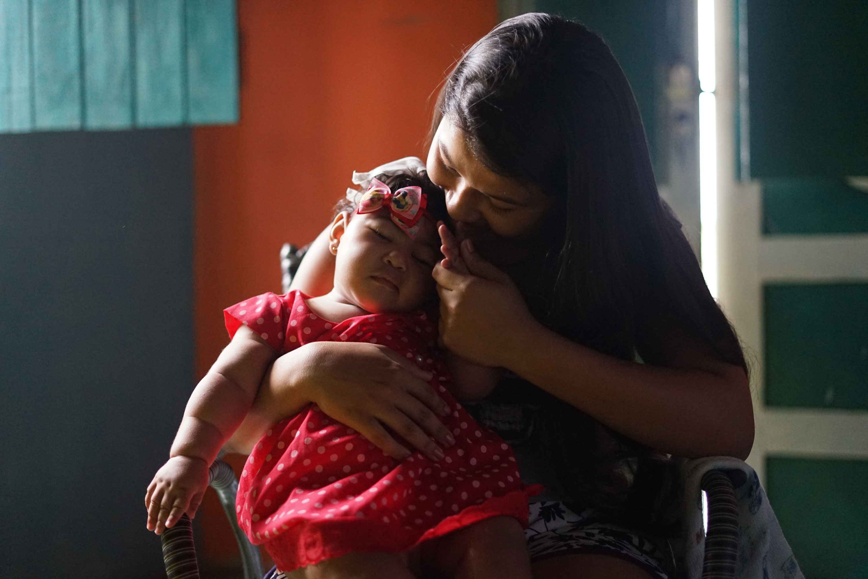 A mother cradles her daughter, who was born with congenital Zika syndrome. 