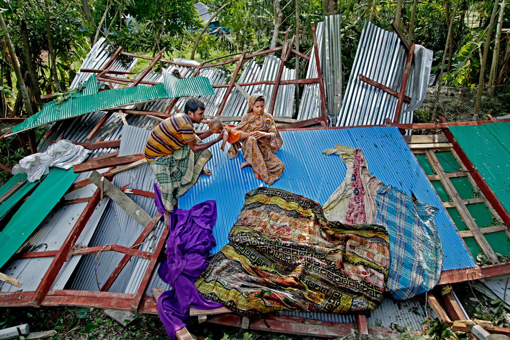 A family mourns atop the ruins of their house, destroyed by 2019 cyclone Fani.
