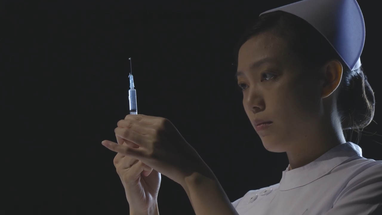 A female nurse holds up a vaccine.