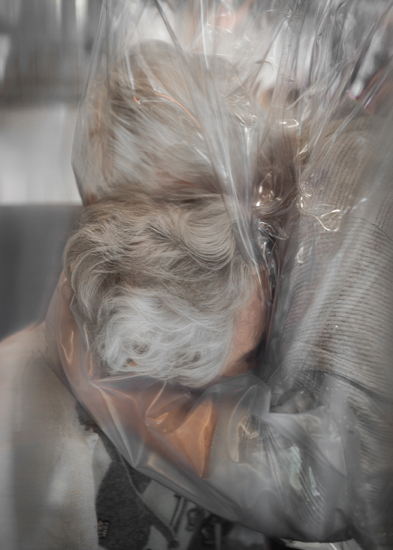 A mother and daughter hug through plastic sheeting, during the Covid-19 pandemic.