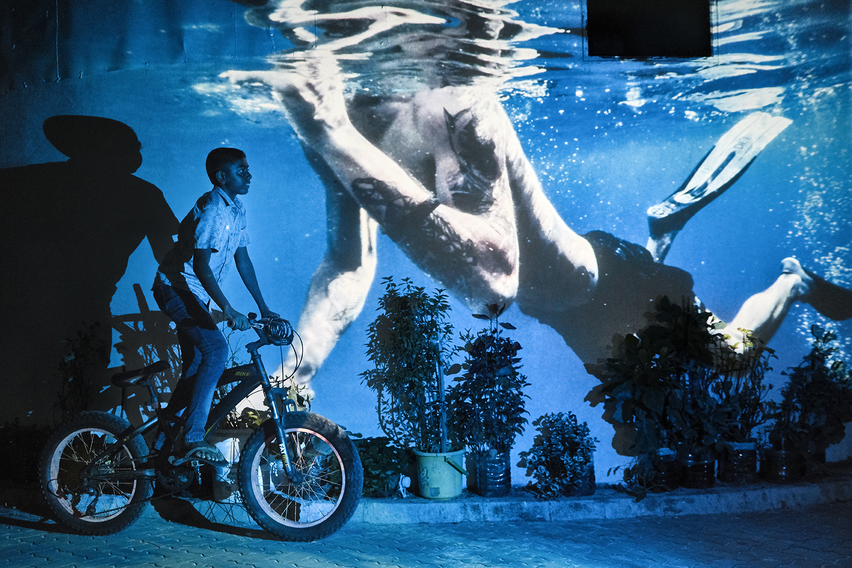 An underwater image is projected behind a man on a motorbike.