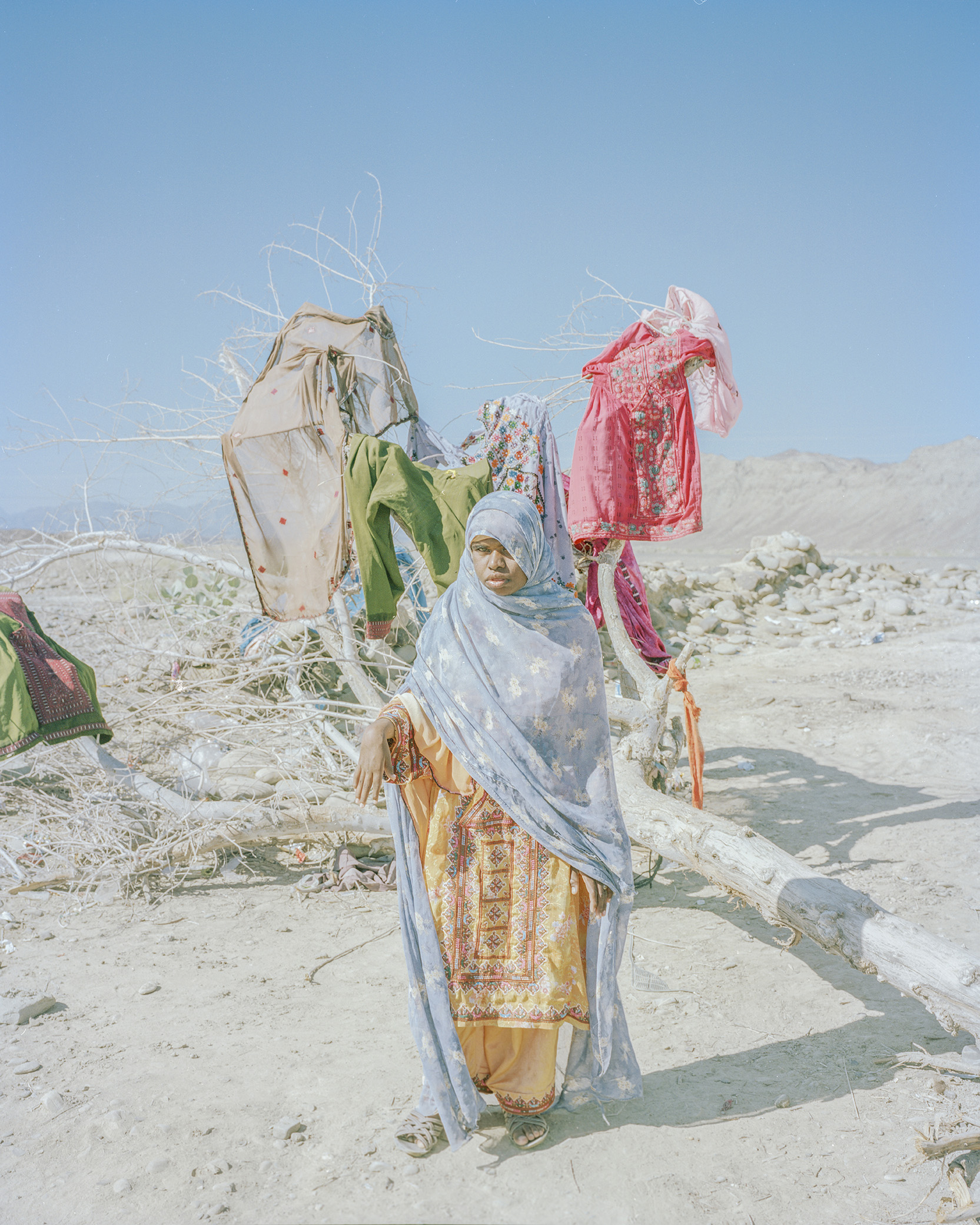 A young woman uses a dead tree for drying clothes. 