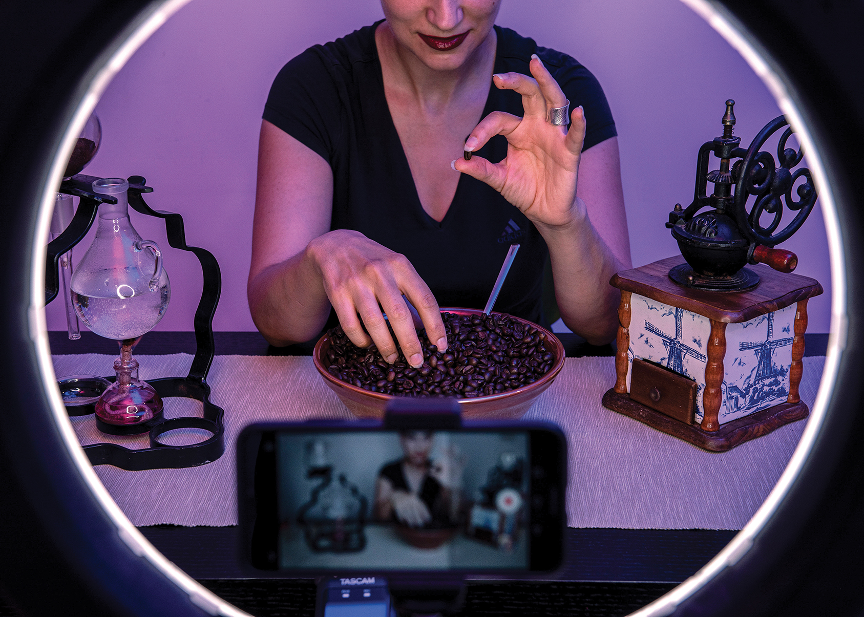 An ASMR artist records a video using an old coffee grinder and beans to make soft sounds.