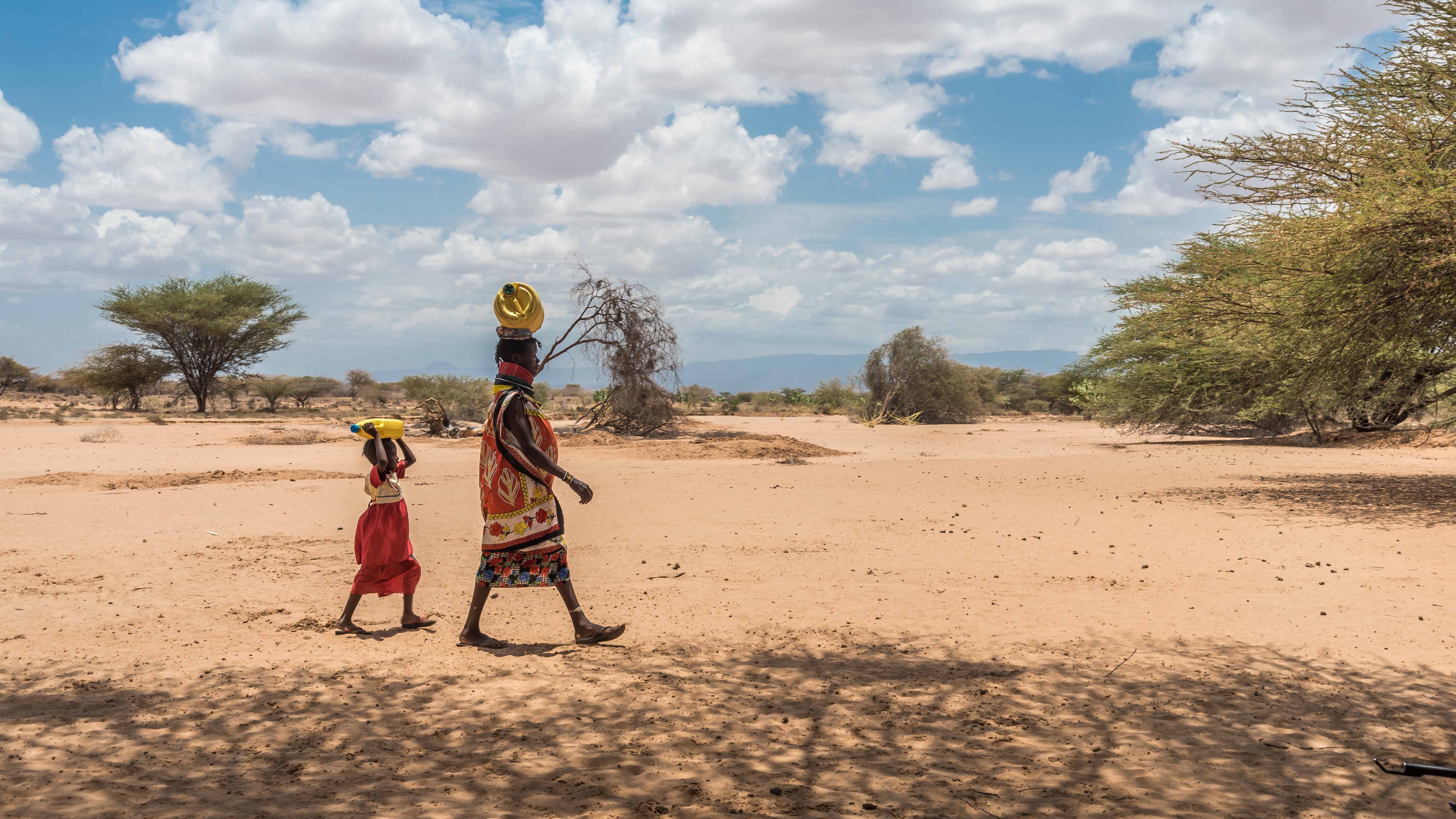 A woman and child walking and carrying water.