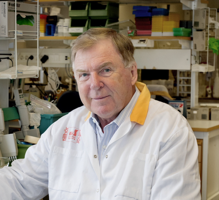 Professor Jan Holmgren sits in a laboratory wearing a white lab coat.
