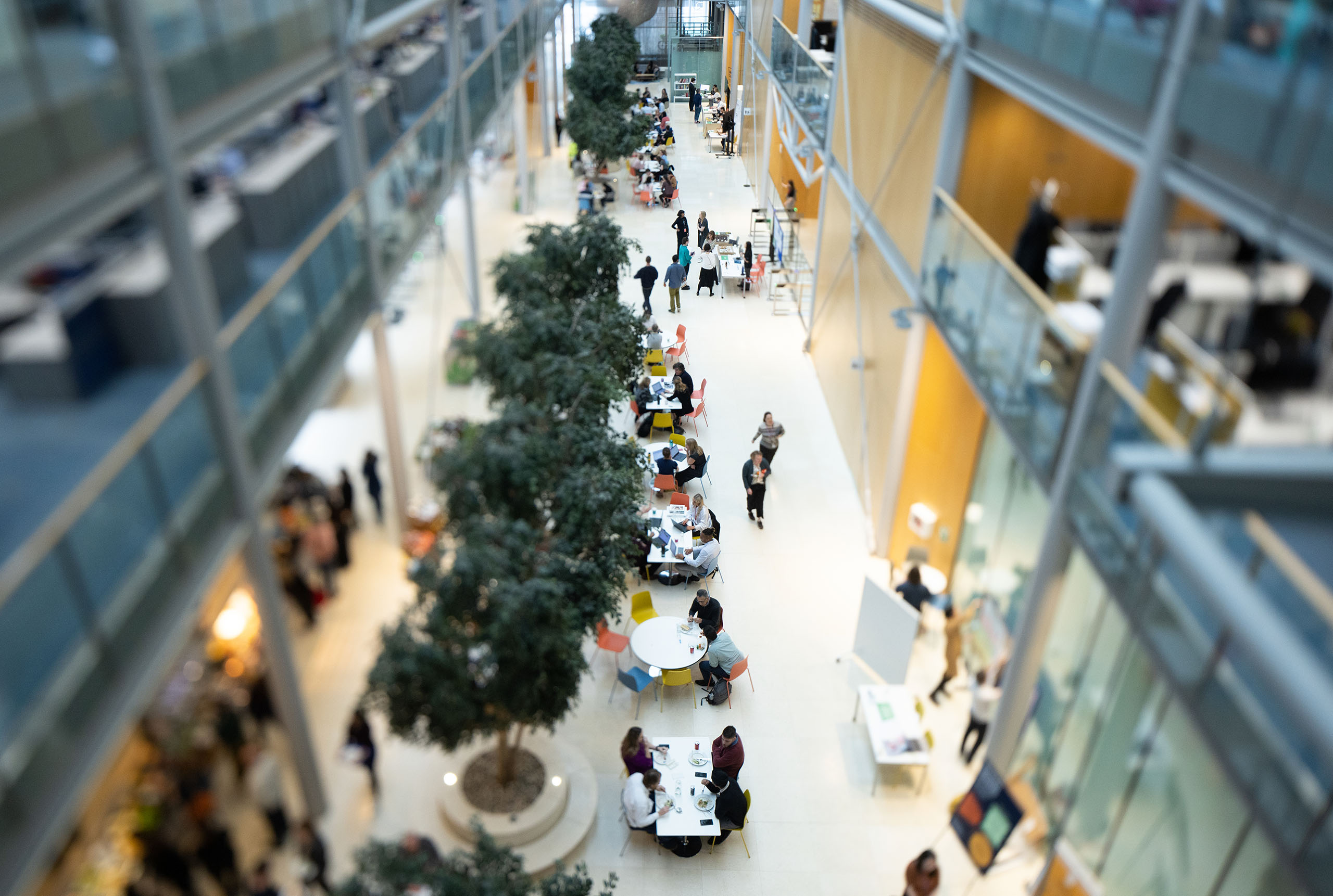Aerial view of Wellcome staff sitting at tables and walking along the office ground floor.