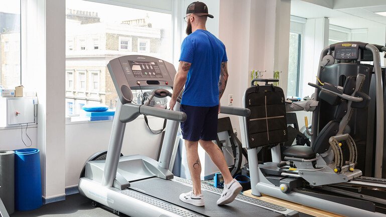 A man wearing sportswear walks on a treadmill.