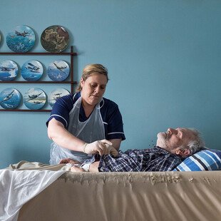 A care worker helps a man change his pyjamas