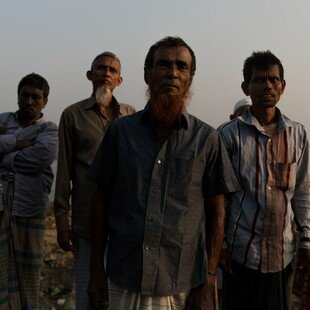 A man, standing in a group, who has lost his home twice due to land erosion 