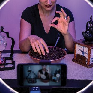 An ASMR artist records a video using an old coffee grinder and beans to make soft sounds.