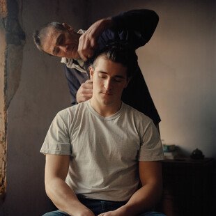 A father cuts his son's hair. 