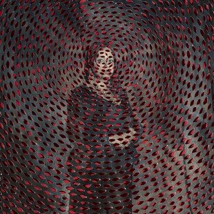 A woman stands against a grey background with red ellipses overlaid in a circular pattern.

