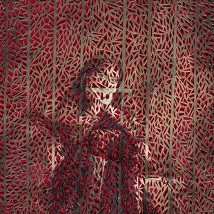 A woman sits for a portrait holding her head in hands with red pattern overlaid.