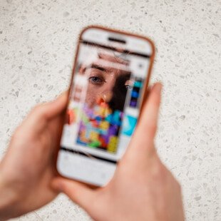 A healthcare worker holds a smartphone in their hands playing a game of Tetris.