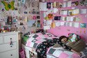 A girl who has been having chemotherapy lays on her bed, surrounded by cards on her walls from the people who love her