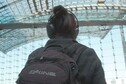 The back of artist Sybille Neumeyer who is wearing headphones and a backpack