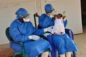 Two medical workers hold up baby Noubia, the last known patient to contract Ebola in Guinea