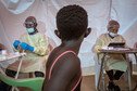 Young girl watches Ebola response team prepare vaccination equipment.