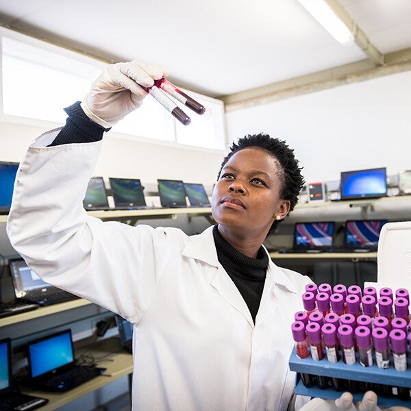 Staff member at the Africa Health Research Institute, KwaZulu-Natal, holding up test tubes in the lab.