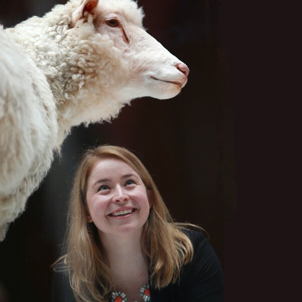 A smiling blonde woman looks up at Dolly the sheep in one of the new science and technology galleries. 