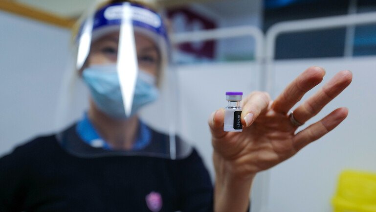 A healthcare worker holds up a dose of a Covid-19 vaccine.
