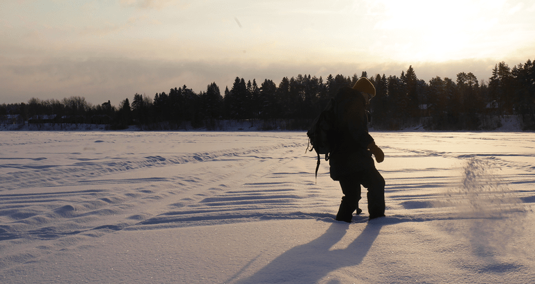 A woman kicks away soft snow in Ii, Finland, to clear a spot for ice fishing.