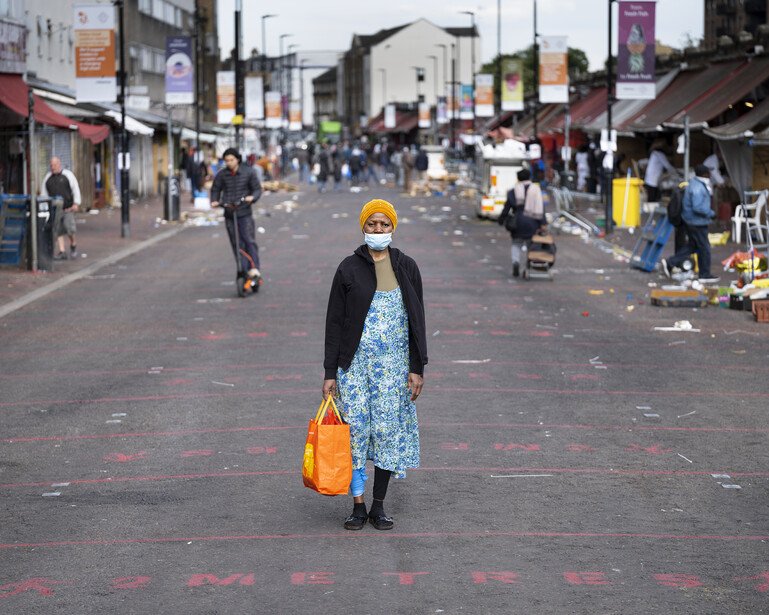 A portrait of a masked pedestrian on London's Ridley Road.