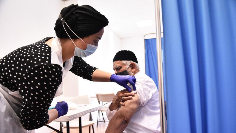 A woman administers a Covid-19 vaccine to a patient at a pop up vaccination centre