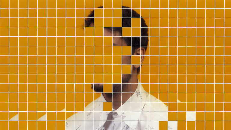 A wall with orange tiles. Some of the tiles have been removed revealing an image of a man's head an shoulders.