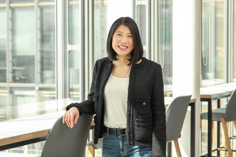 Maggy Chan, Chief Operating Officer at the Wellcome Trust, stands smiling at the camera in a bright, modern office.