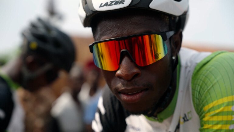 Kondema Kargbo wearing a cycling helmet and reflective sunglasses during a cycling event.