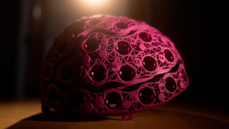 Close-up of a purple 3D-printed helmet with a lattice structure and multiple circular sensor housings.