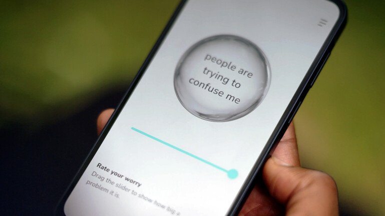 A phone screen shows a bubble reading “people are trying to confuse me” above a “Rate your worry” slider.