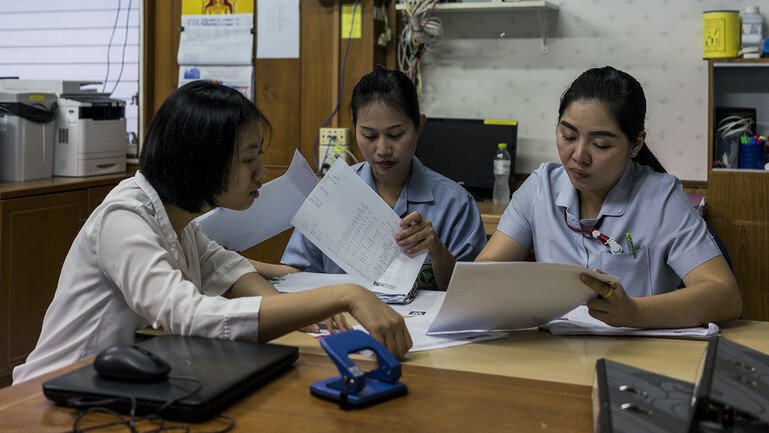 A researcher and two nurses look at patient data.