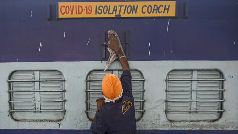 A worker cleans the exterior of a train coach that has been converted into a Covid-19 isolation ward.