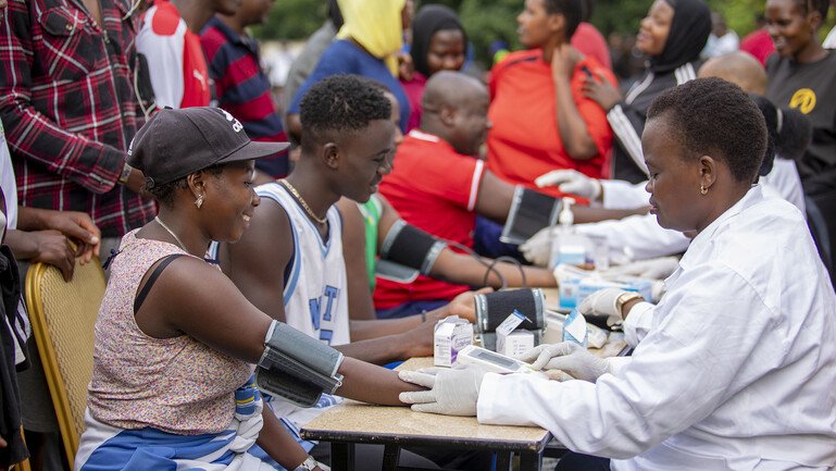 People sat at a table get vaccinated against Ebola as part of a community event.