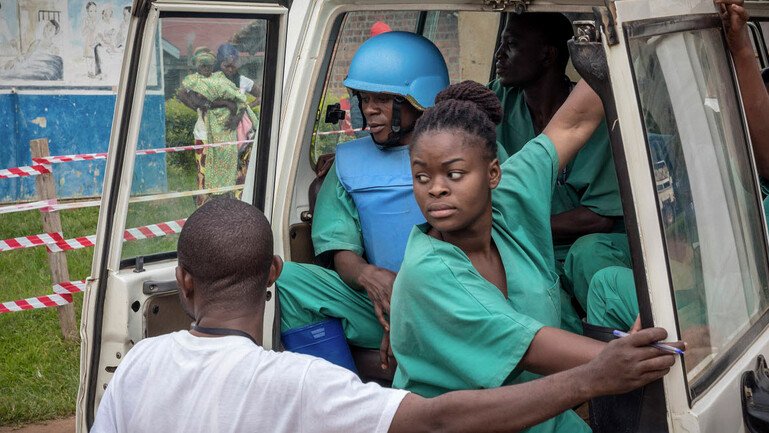 An Ebola response team in DRC, under the protection of UN troops wearing bulletproof vests and helmets.