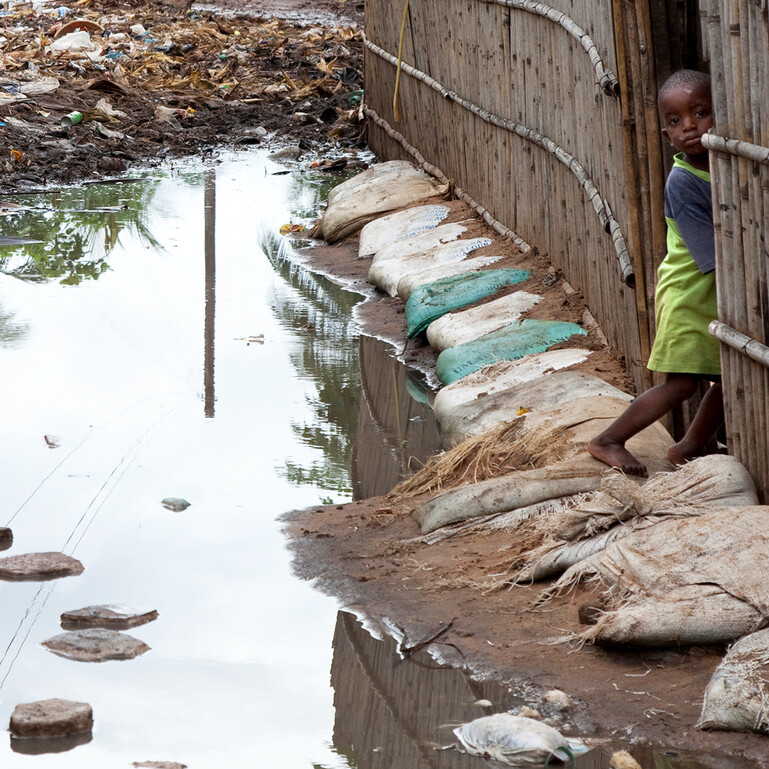A child looks at rainwater on a flooded street in Mozambique.