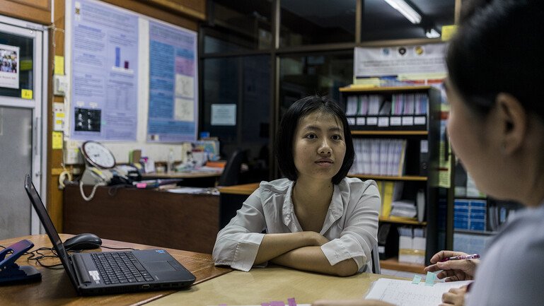 Cherry Lim sitting at a desk, talking to nurses