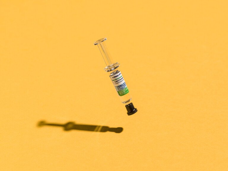 A vaccine vial against an orange background