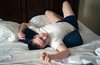 A 19-year-old man who is on the autistic spectrum lying on a bed playing with a piece of string