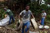 Four men collecting waste and old appliances from a ravine to eliminate mosquito breeding sites