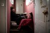 Two women sit on the stairs in their flat.