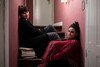 Two women sit on the stairs in their apartment.