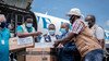 Airport staff and health personnel handle boxes with doses of AstraZeneca Covid-19 vaccines.