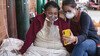 A Covid-19 patient breathing with the assistance of oxygen and her daughter sitting on a bed in a hospital talk to relatives through a mobile phone.